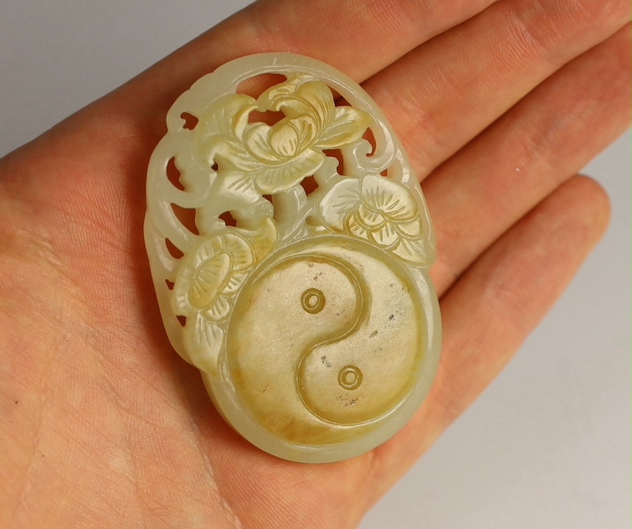 A Chinese white and russet skin jade oval plaque, 19th century, 6.4cm, wood stand